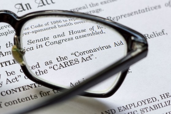 A pair of glasses magnifies text on a paper about COVID-19 related unemployment benefits.