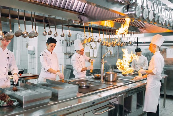 Chefs cook the menu selections of customers in a restaurant kitchen.