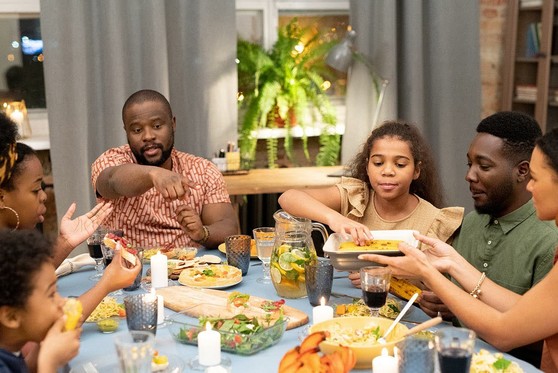 An African-American family sits together to eat around the dinner table.