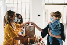 A mother holds her son as she takes a bag of food at a food bank.