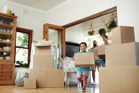 A family brings boxes into their new home.