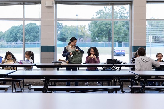 Grade school students eat lunch in a school cafeteria.