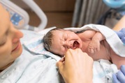 A mother lays in a hospital bed with her newborn child.