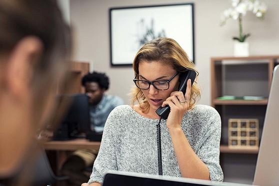 An administrative professional speaks on the phone.