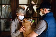 A woman receives her grocery order delivered to her residence.