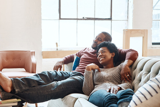 An African American couple relax together on a couch.