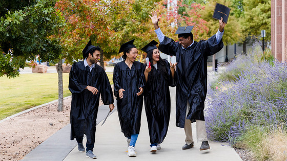 College graduates walk together and celebrate.