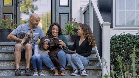 A family sits in front of their house.