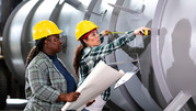 Female workers measure a large cylinder.