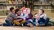 Young children sit together, play, and hug each other.