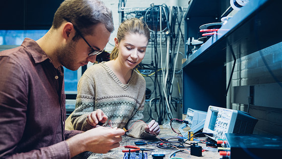 Young workers connect electrical components of devices.