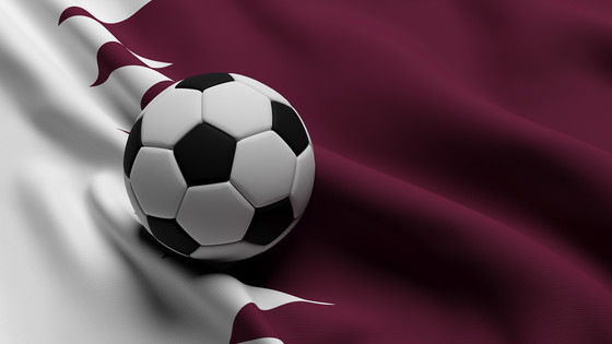 A soccer ball with the flag of Qatar in the background