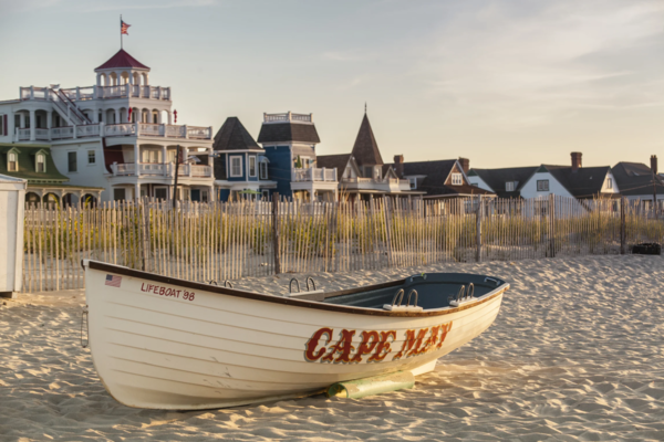 A rescue boat sits on the beach in Cape May, NJ, with homes and hotels in the background..
