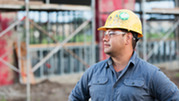 A construction worker stands in front of a scaffolding.