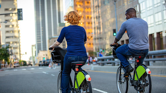 A woman and a man ride on their bikes down a city street.