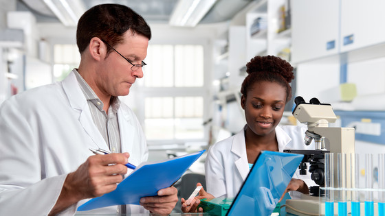 Two scientists use a microscope as part of their lab research.