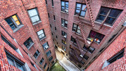 A view of an apartment complex from a high level, looking down at the brick structure with windows and fire escapes.