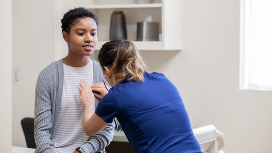 A nurse uses a stethoscope to listen to a patient's heartbeat.