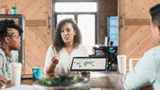 A woman ponders business decisions with her colleagues while they drink coffee together at a cafe.