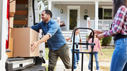 A family unloads their boxes from a van to move into their new house.