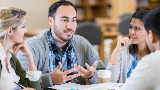 Four people sitting together and chatting with one another at a coffee shop.