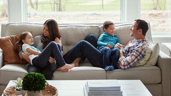 Two parents relax on their living room couch with two children.