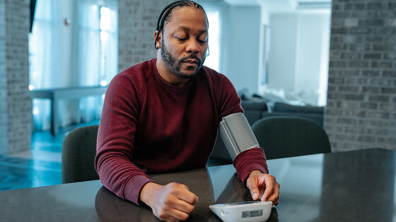 African American male tests his blood pressure  