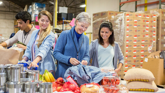 Cheerful Caucasian senior female food bank director talks with a group of volunteers.