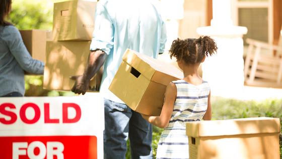 Family carries moving boxes into their home 