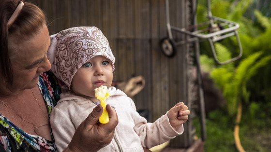 An older woman feeds a young girl.