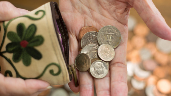 A close-up of a wallet dumping coins into a hand