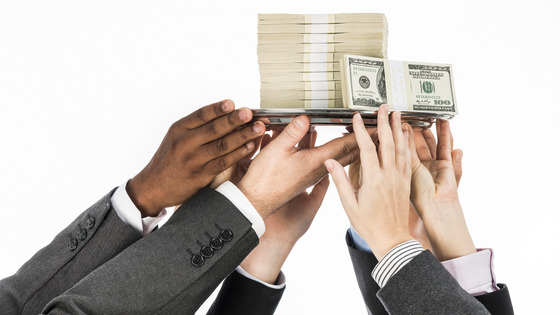 Several people hold up a plate of money.