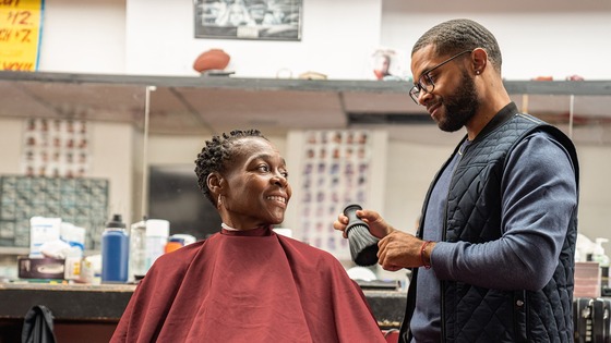 A hair stylist with a brush talks with a client at a salon.