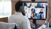 Person participates in webinar on desktop computer in office 