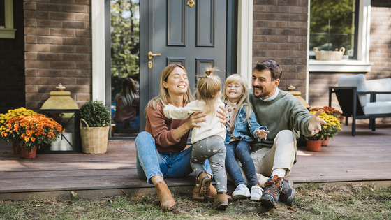 Two small children with their parents sitting on a doorstep