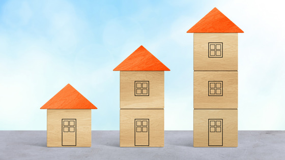 Three wood block houses of different heights standing together in a row