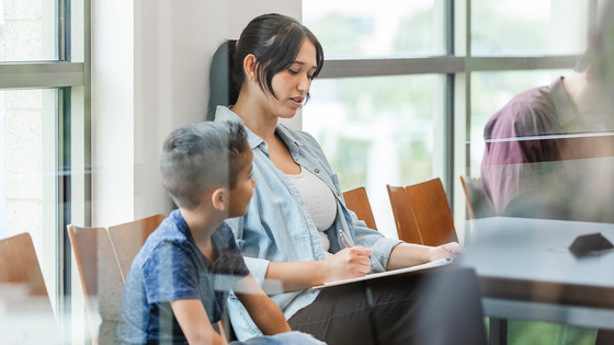 A mother fills out forms for her sick child in the waiting room of a medical office.