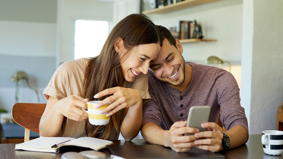 A couple enjoying time together while sitting at a table and looking at a phone