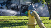 A fire hydrant in use on a lawn. 