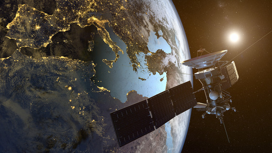 A satellite orbits Earth above glowing city lights.