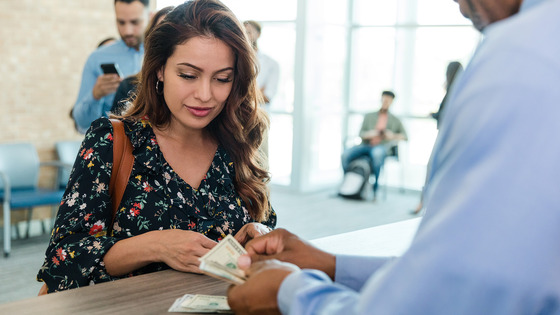 A woman counts cash at a service counter.