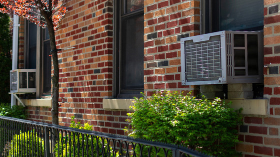 An apartment building is shown with window-mounted air conditioning units.