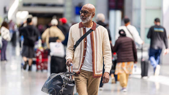 A traveler walks through an airport pulling a suitcase.