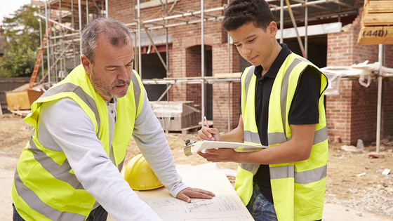 Two people review construction plans at a work site.