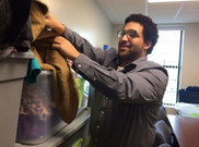 AmeriCorps member Tim Gustav sorts coats at United Neighbors. (Photo by Deborah Allard/Herald News)