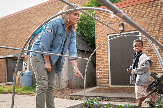 FoodCorps AmeriCorps member Sarah Schroeder points at plants in the garden at Durant-Tuuri-Mott Elementary in Flint, MI.