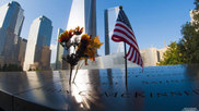 A flower and American flag are left in honor of 9/11 victims at the September 11th Memorial in New York City.