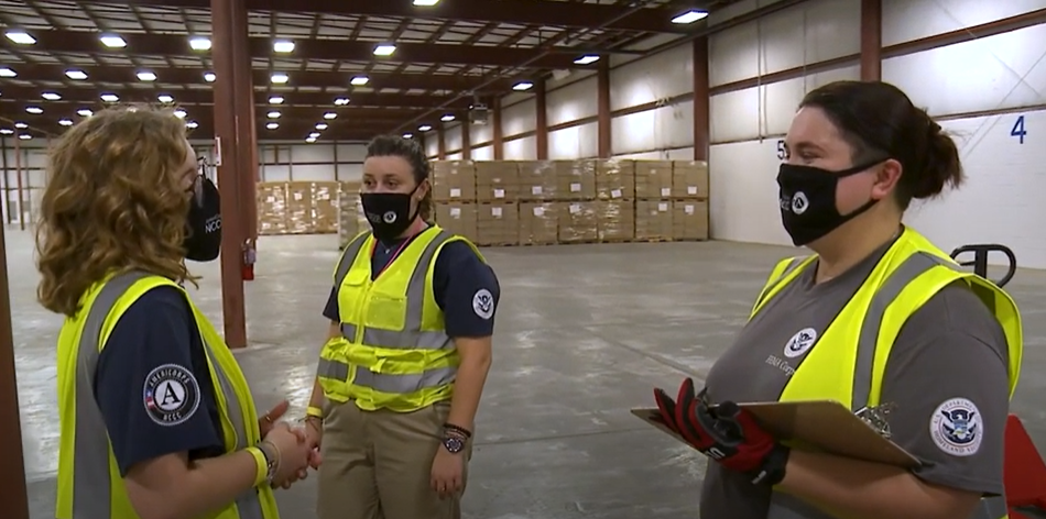 Three FEMA Corps members talking with each other in a warehouse
