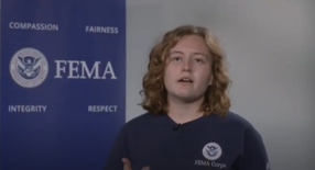 FEMA Corps member speaking to camera in front of FEMA banner