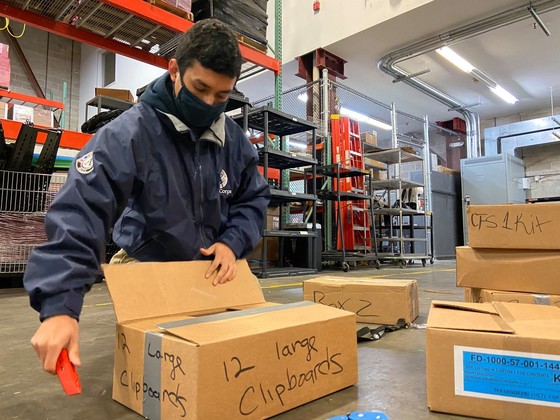 FEMA Corps member packing a box in a warehouse